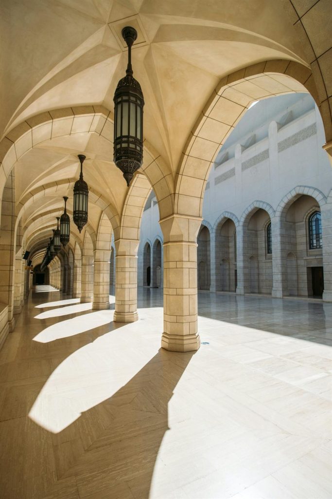 An arched stone corridor lit by hanging lanterns