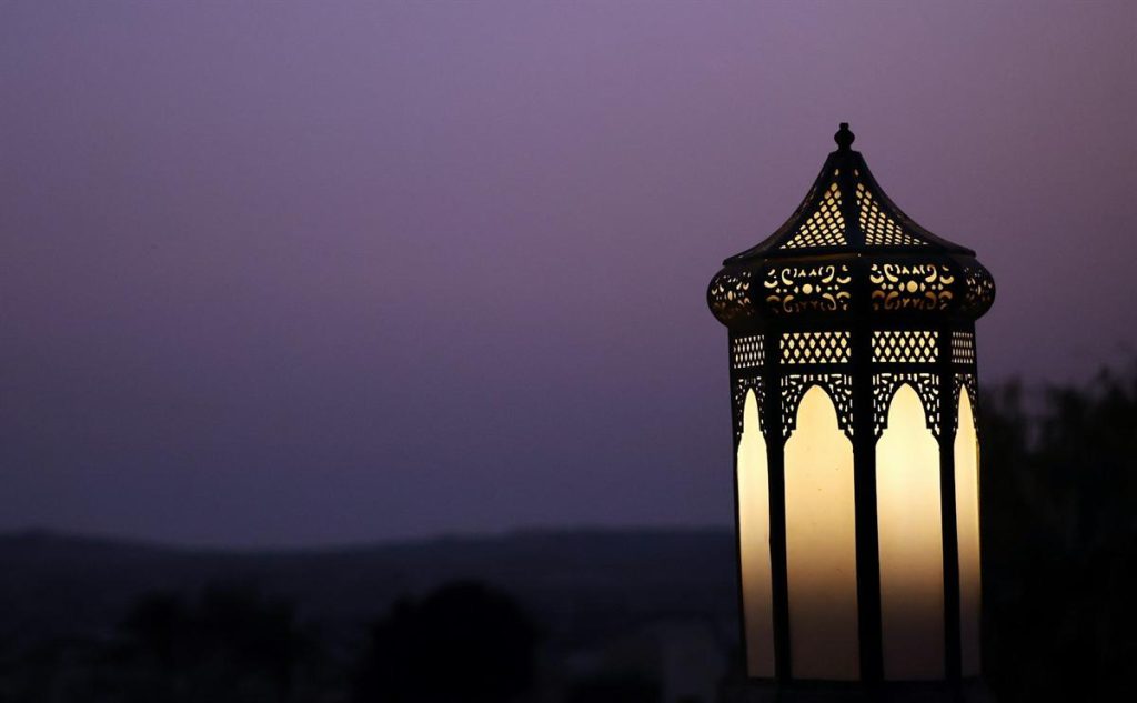 An ornate lantern glowing against a twilight sky