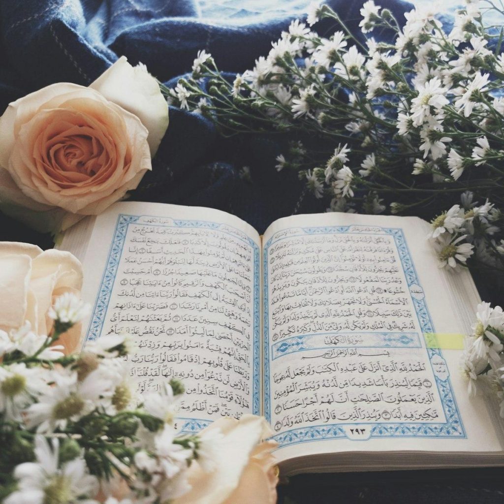 An open Quran surrounded by soft flowers